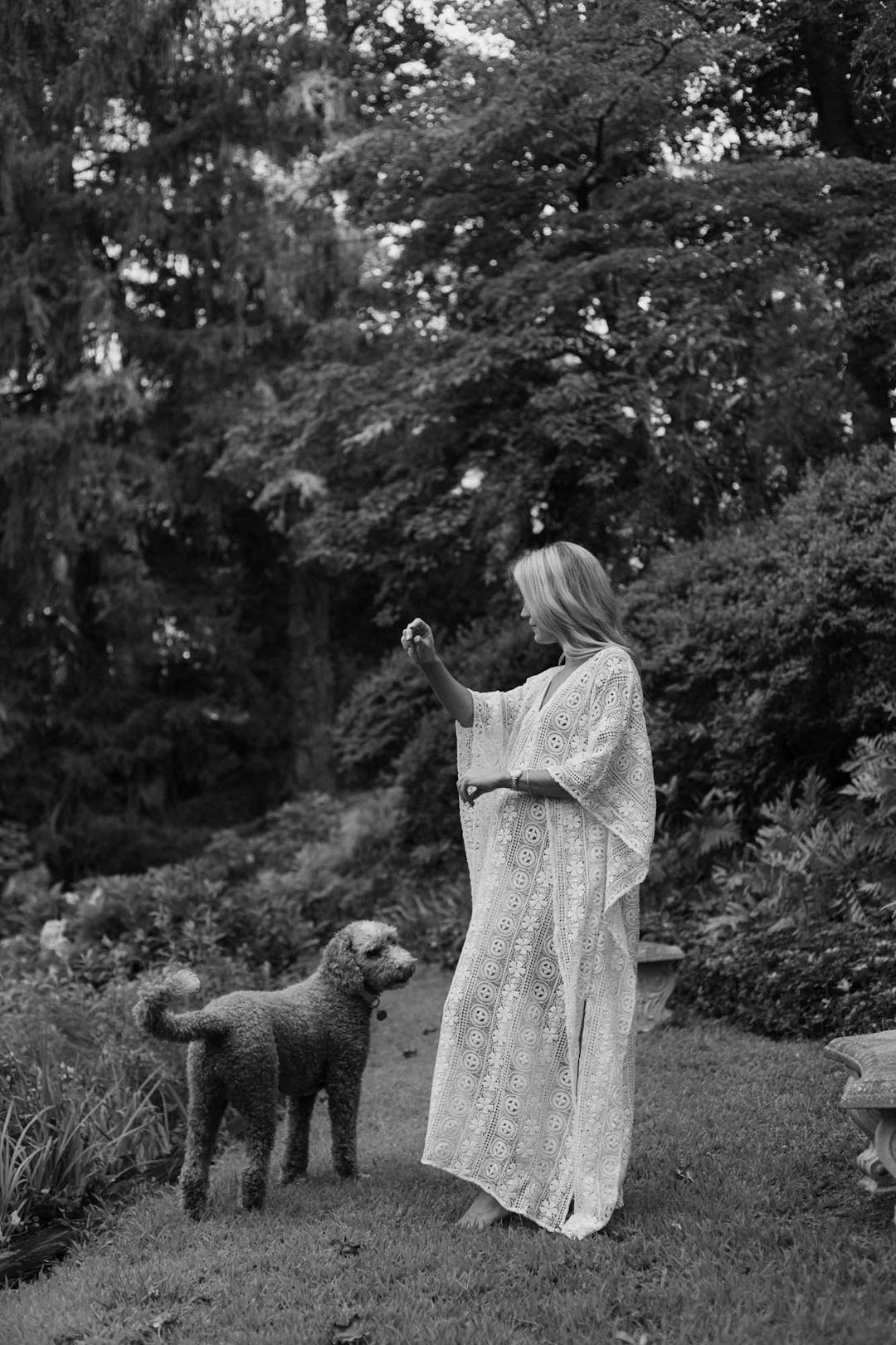 black and white medium format maternity portrait of woman in white dress playing with golden doodle
