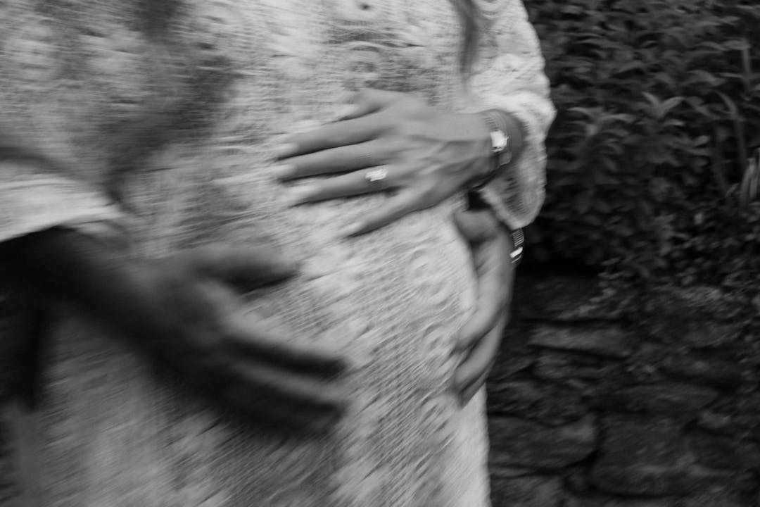 blurry black and white portrait of woman's hands on belly