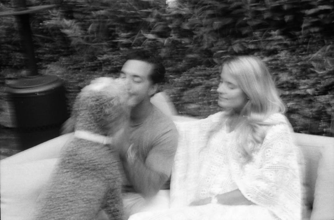 blurry black and white portrait of couple with dog on outdoor couch
