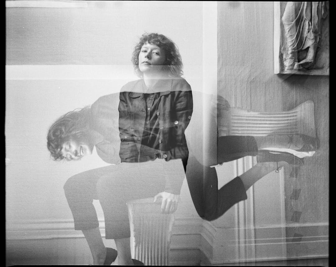 black and white medium format double exposure of woman sitting on column