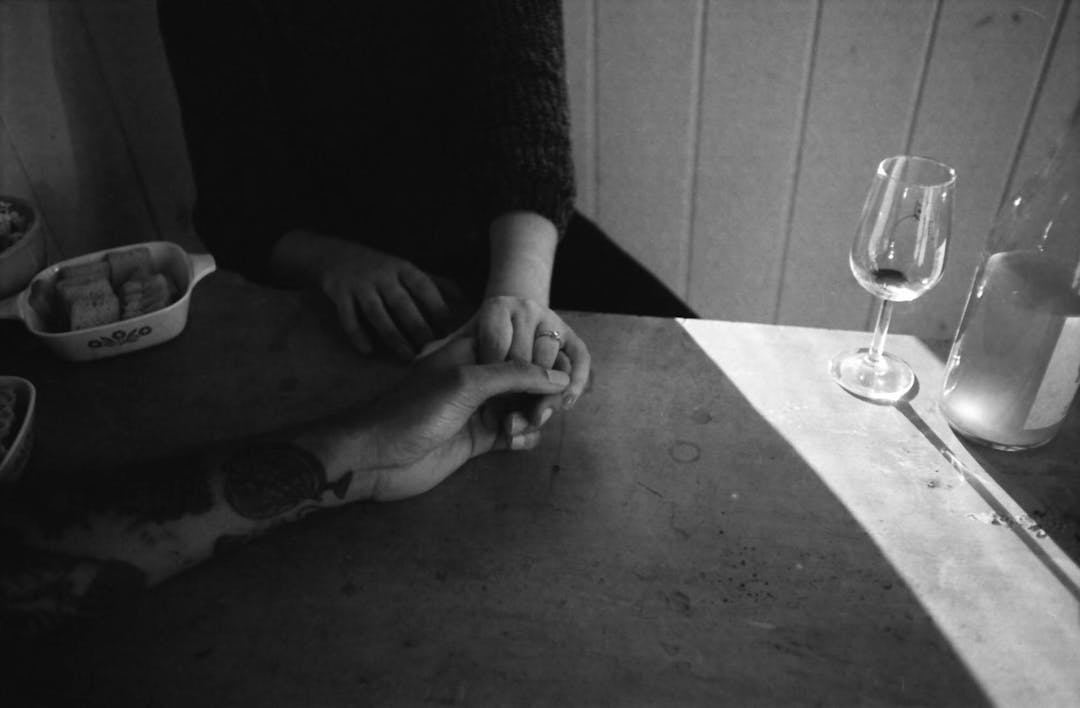 black and white photo of couple holding hands at table with wine glass