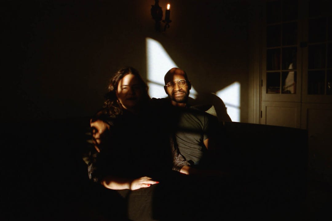 color photo of couple seated on couch with geometric shadows