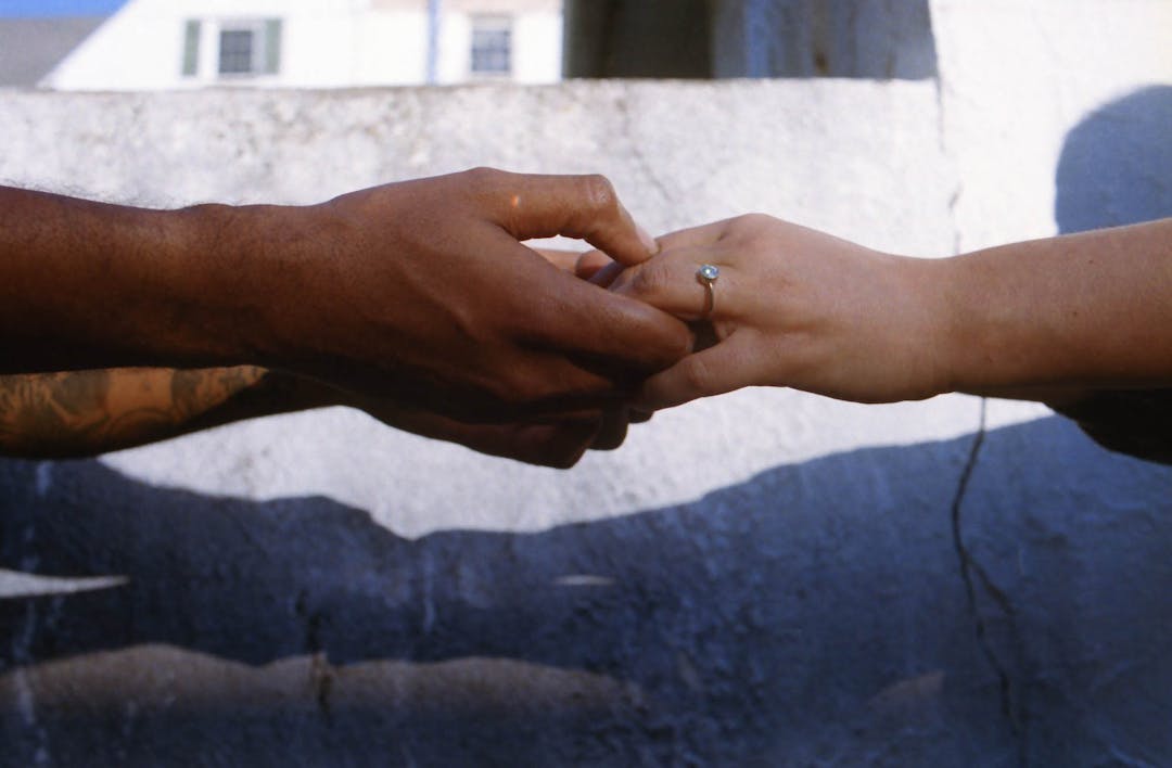 color film photo of couple holding hands with engagement ring
