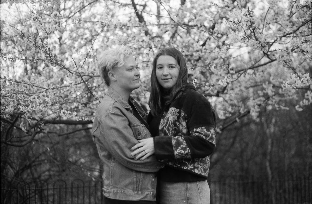 black and white film photo of couple in front of cherry blossoms