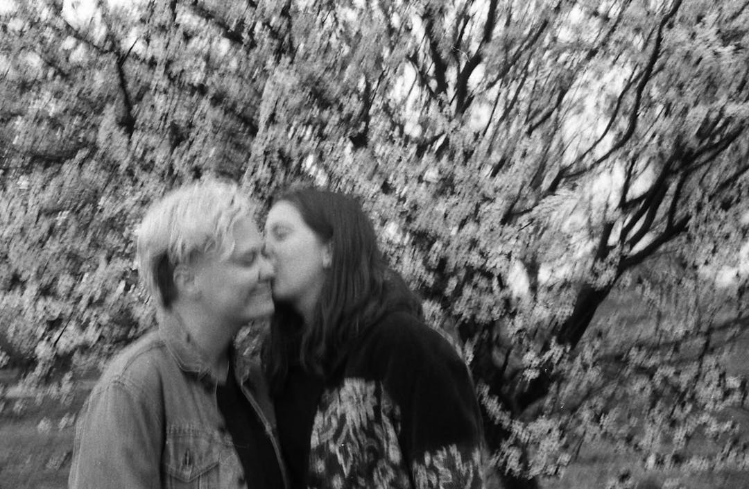 blurry black and white film photo of couple in front of cherry blossoms