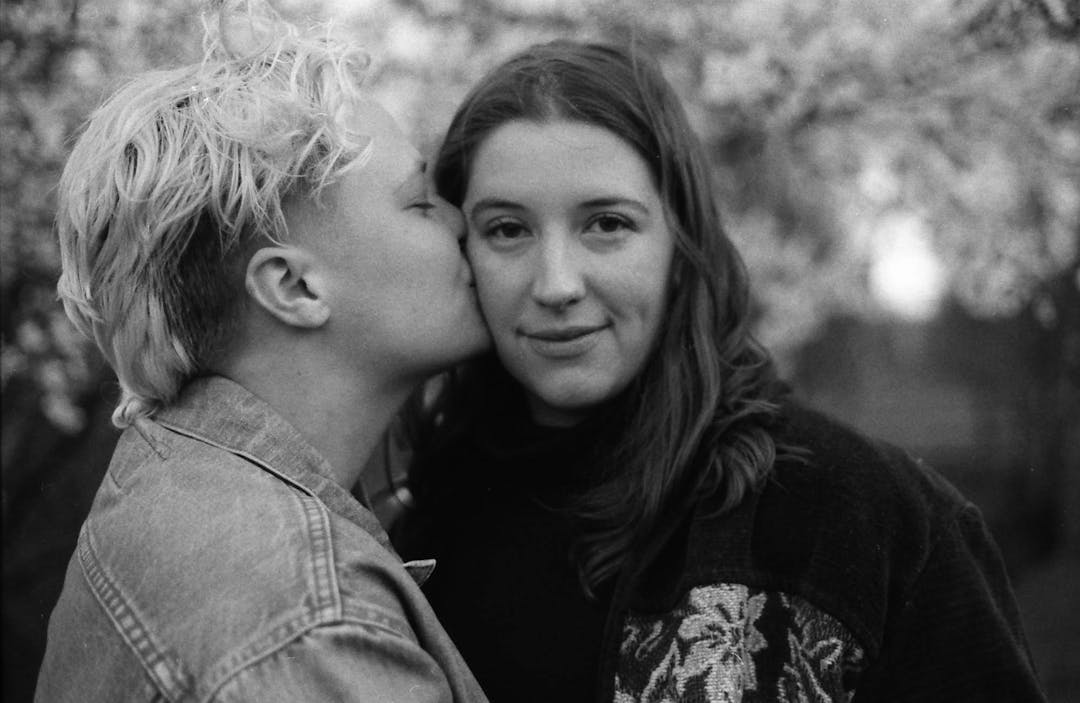 black and white photo of woman kissing another woman's cheek