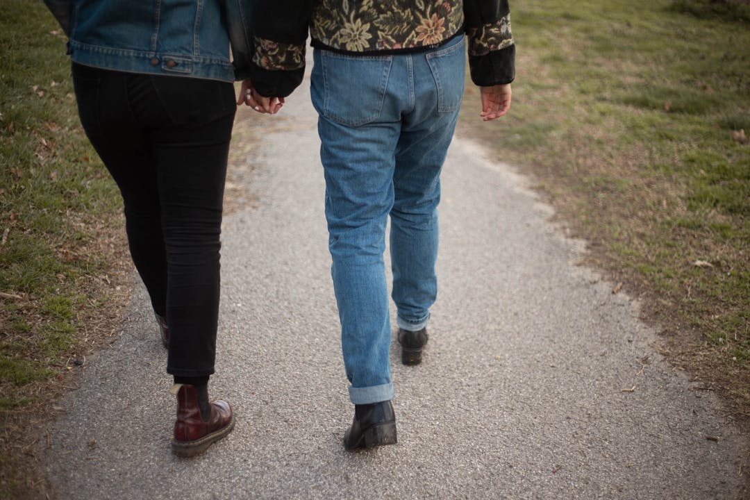 color photo of two woman walking down path holding hands