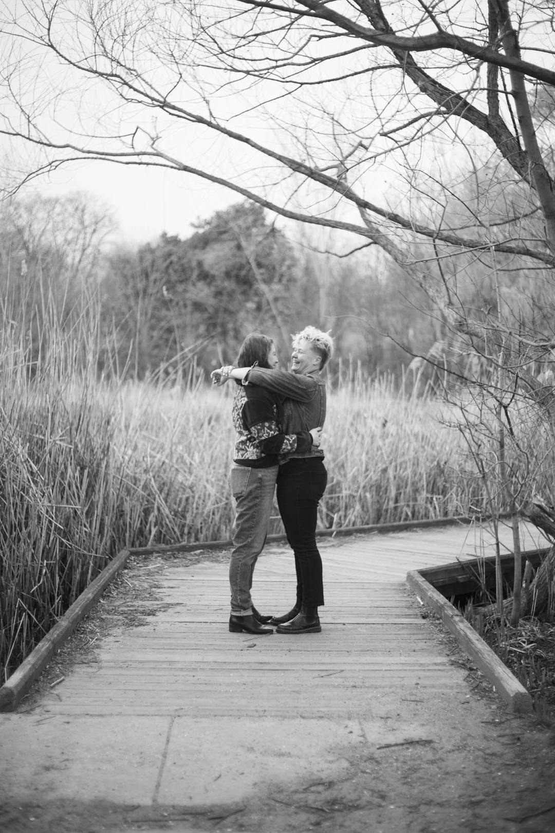 black and white photo of couple hugging on boardwalk at patterson park pagoda in baltimore