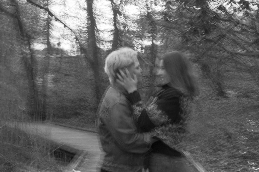 blurry black and white photo of couple hugging on boardwalk