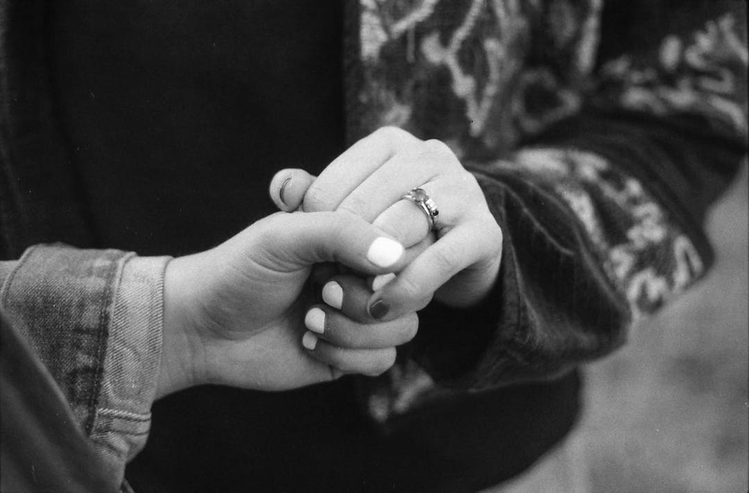 black and white photo of two woman holding hands with engagement ring