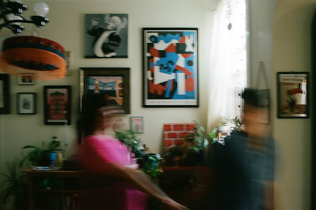 blurry color film photo of two women walking past art