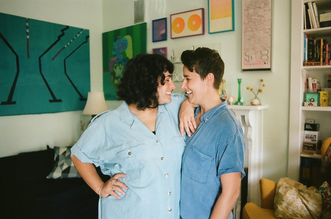 blurry color film photo of couple laughing in colorful and art-ful livingroom 